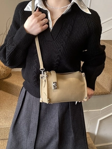 Minimalist khaki leather crossbody bag with lychee texture and metal clasp on a model