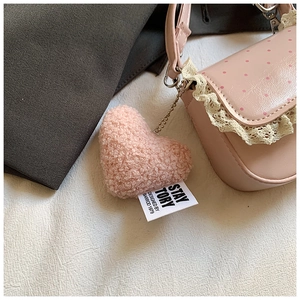 Détail d'un sac à main rose à pois avec bordure en dentelle et breloque en cœur