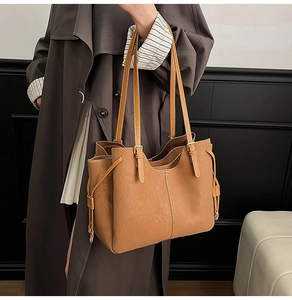 Detail of tan leather tote bag with white contrast stitching and side drawstring