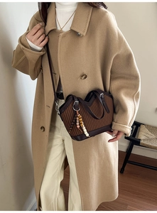 Gros plan d'un sac seau plissé marron foncé avec pompon en perles vintage et anse en cuir