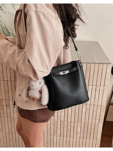 Détail du sac seau en cuir grainé noir avec fermoir rotatif argenté et porte-bonheur