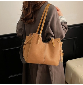 Detail of vintage brown suede tote bag featuring side drawstrings and slim shoulder strap