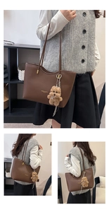 Detail of dark brown tote bag with pebble leather texture and cute plush puppy charm