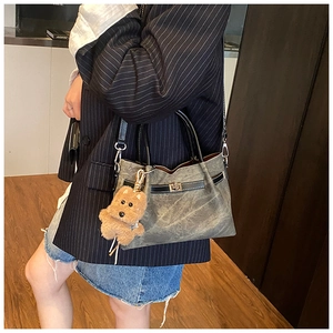 Detail of vintage tote bag with metal turn-lock closure and bear charm accessory