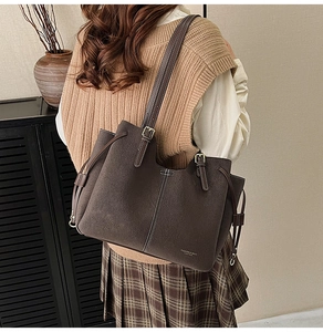 Close-up of brown tote bag with white contrast stitching and gold metal buckle detail