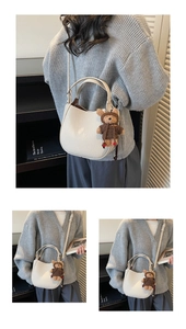 Detail of off-white lychee texture leather hobo bucket bag with a cute bear charm