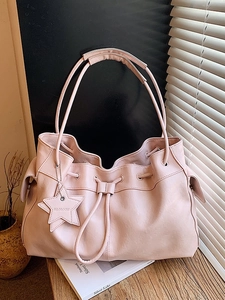 Pink drawstring leather bucket bag with star charm on wooden table with warm lighting