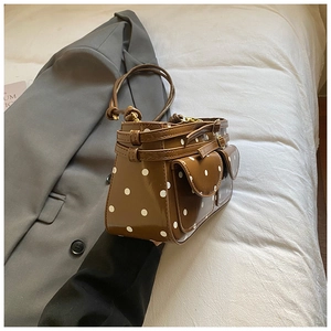 Sac sous le bras marron à pois blancs avec deux poches à rabat sur un blazer gris