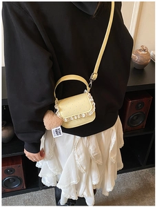 Détail du mini sac jaune à pois avec bordure en dentelle blanche et breloque ours brun