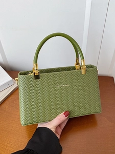 Minimalist grass green woven handbag with golden round handles and textured finish