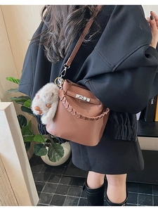 Détail du sac seau en cuir grainé marron avec poignée tressée et fermoir pivotant argent