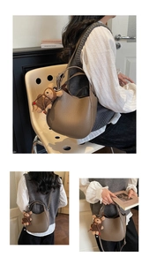 Detail view of brown pebbled leather bucket bag with plush bear charm and adjustable strap
