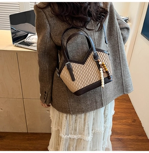 Détail d'un sac seau bicolore avec texture plissée crème et touches de cuir marron