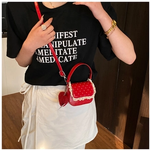 Détail du mini sac rouge à pois avec bordure en dentelle et pendentif cœur doux