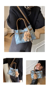 Detail of light blue denim bucket bag with brown leather handles and plush bear charm