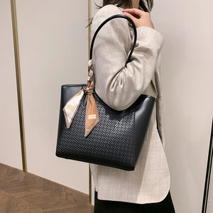 Elegant black woven tote bag with smooth leather trim and decorative geometric silk scarf
