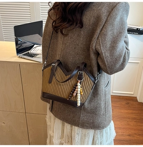 Détail d'un sac plissé kaki avec bordure en cuir marron et breloque perlée ethnique