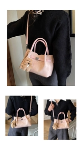 Detail view of pink crossbody bag with metal buckle and brown teddy bear charm
