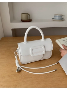 Detail of white PU leather handbag featuring a square buckle and silver heart charm pendant