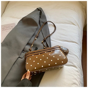 Détail d'un sac à bandoulière marron à pois avec texture PU brillante et breloque cœur