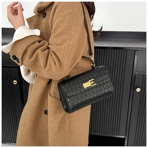 Dettaglio della borsa in pelle intrecciata nera con chiusura dorata sulla modella