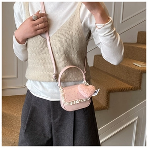 Détail du sac à bandoulière rose avec bords en dentelle, pois rouges et pendentif cœur