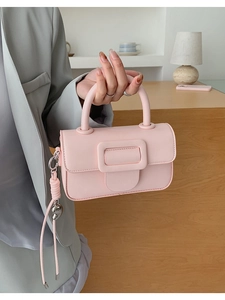 Detail of pink leather handbag featuring a large square buckle and heart charm