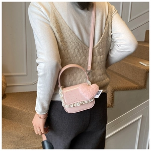 Détail du sac à bandoulière rose à pois avec dentelle et pendentif cœur en peluche