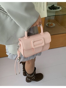 Pink faux leather handbag with square buckle and heart charm in a lifestyle setting
