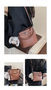 Détail d'un sac seau marron grainé avec poignée tressée et breloque lapin en peluche