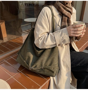 Close-up of olive green suede tote bag with decorative buckle detail on bottom corner