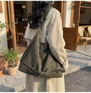 Close-up of olive green suede tote bag texture with adjustable strap and metal buckle