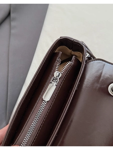 Top view detail of dark brown leather bag showing silver metal zipper and khaki fabric lining