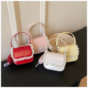 Détail de sacs à pois avec bordure en dentelle et pompons en quatre couleurs
