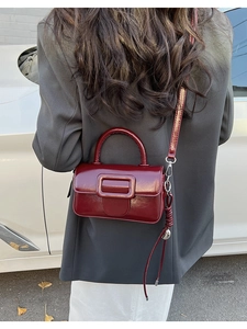 Street style shot of a burgundy vintage mini crossbody bag with glossy faux leather finish
