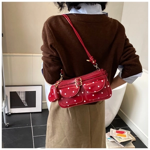 Détail du sac baguette rouge à pois avec poches frontales et accessoire charm en cœur