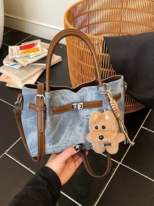 Blue denim bucket bag with brown leather trim and silver turn-lock closure