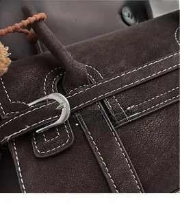 Detail of dark brown pebble leather bag with silver metal buckle and contrast stitching