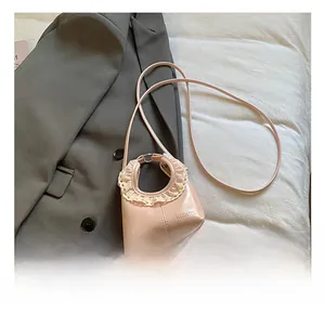Detail view of a pink handbag with white lace trim, metal ring handle, and thin shoulder strap
