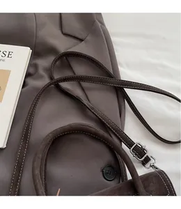 Close-up of dark brown suede handbag with white stitching and silver metal buckle details