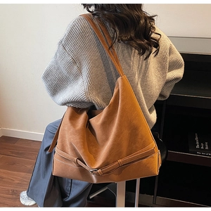 Detailed view of brown suede hobo bag with contrast stitching and decorative buckle strap