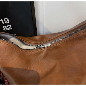 Detailed close-up of brown vintage leather bag with metal zipper and herringbone lining
