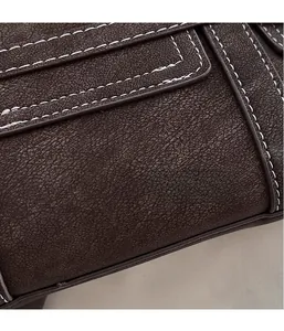 Detailed close-up showing textured dark brown leather with white contrast stitching