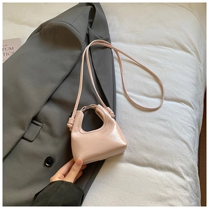 Détail d'un mini sac à main rose sur blazer gris montrant le fini brillant et la bandoulière