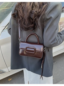 Close-up of a vintage coffee brown glossy leather crossbody bag with square buckle