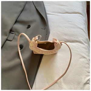 Détail d'un petit sac à bandoulière rose avec bordure en dentelle blanche et anneau en métal