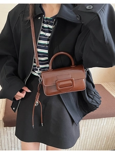 Brown leather handbag with square buckle and tassel detail worn by a model