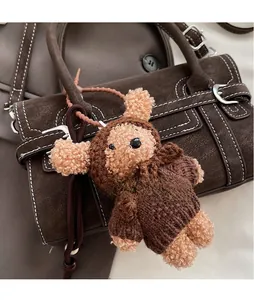Detail of beige teddy bear plush pendant on a vintage brown leather shoulder handbag
