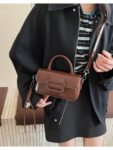 Detailed view of a brown vintage leather handbag with a buckle and heart pendant