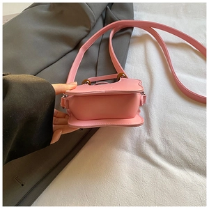 Detail of a pink designer crossbody bag with unique wooden accents and leather texture